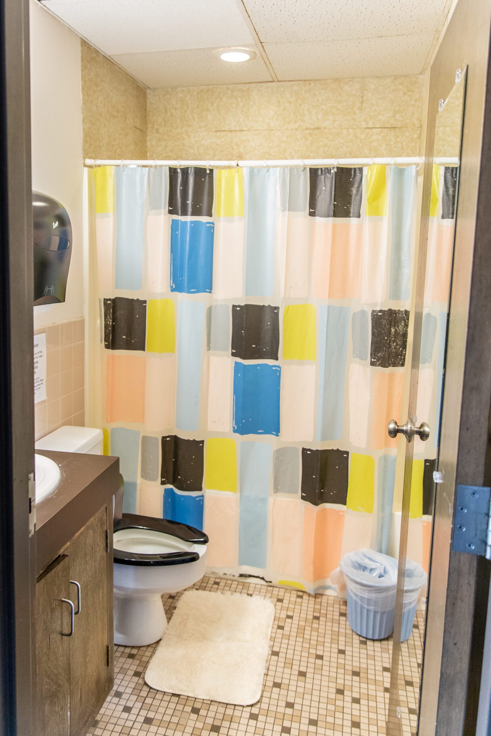 Shared bathroom with toilet, sink, and colorful shower curtain
