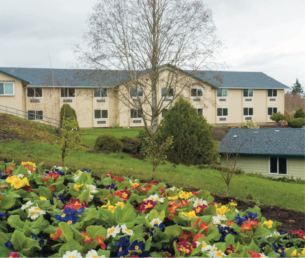 A large rehab facility with gardens and a landscaped front yard.