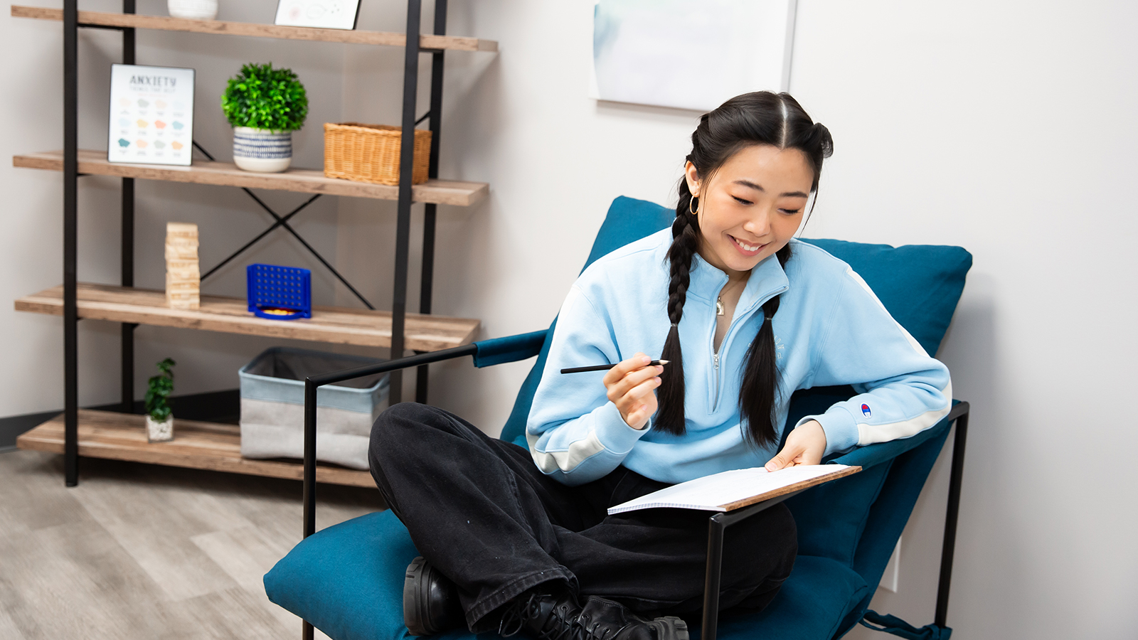 Individual seated in therapy room with wall art and decor.