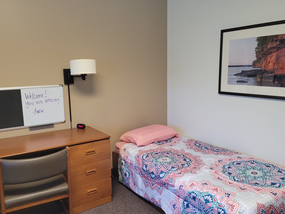 Twin bed with colorful quilt and welcome whiteboard