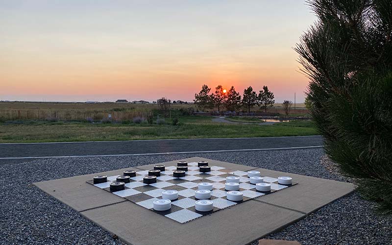 Outdoor checkerboard game with a sunset over open fields.
