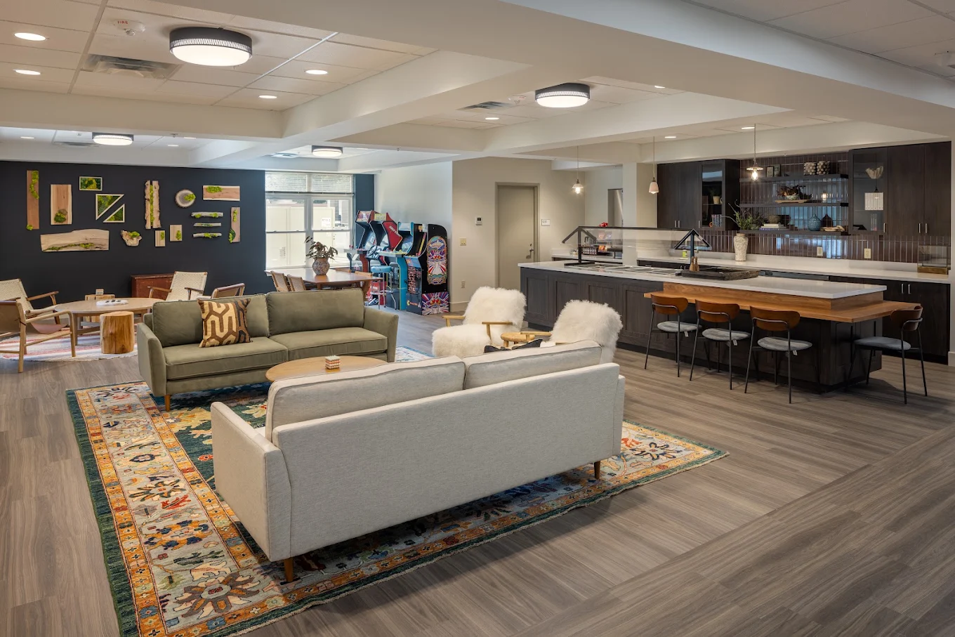 Open living area with sofas, kitchen counter, tables, and arcade games.