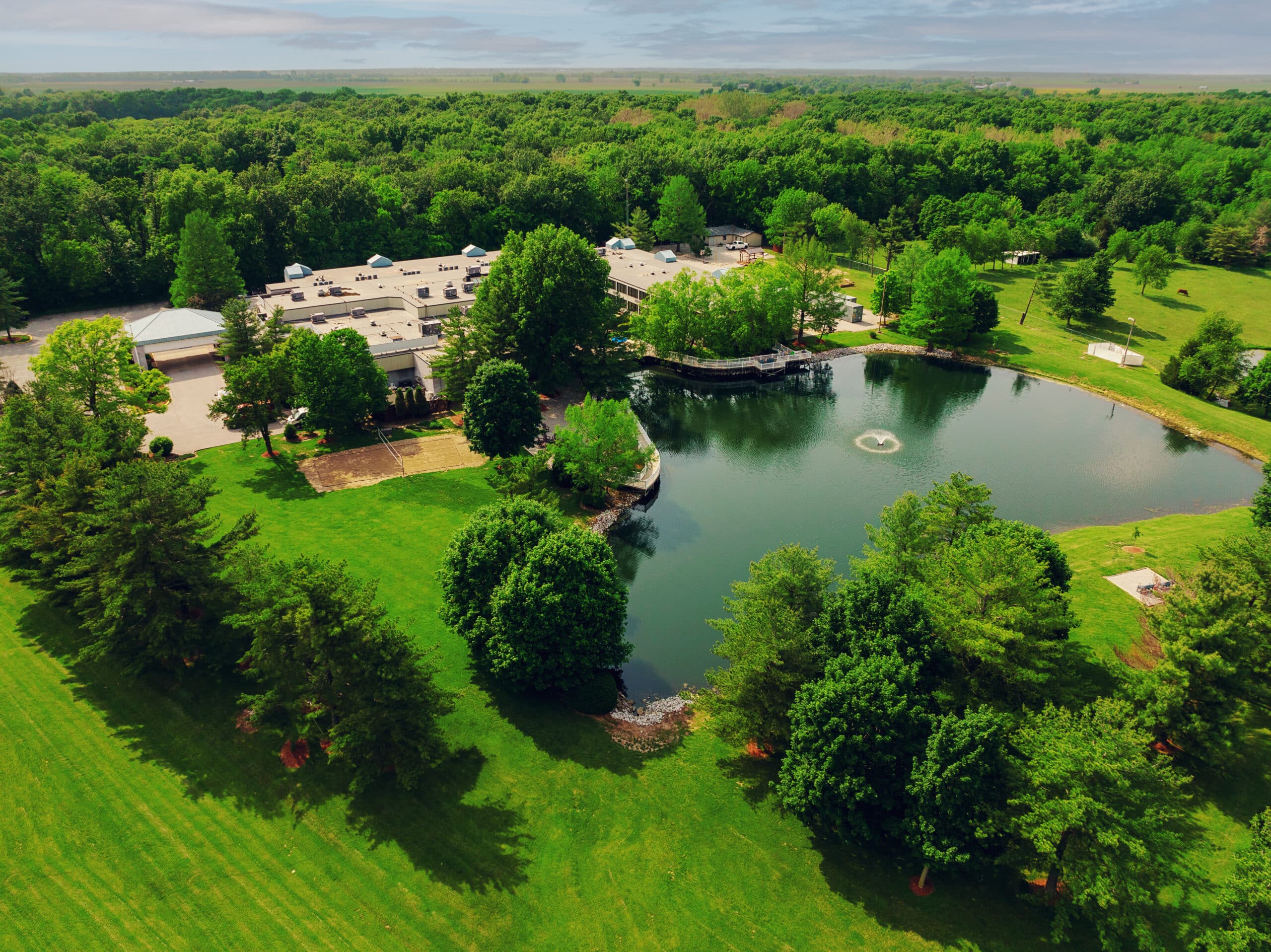 Aerial view of facility with a pond and fountain.