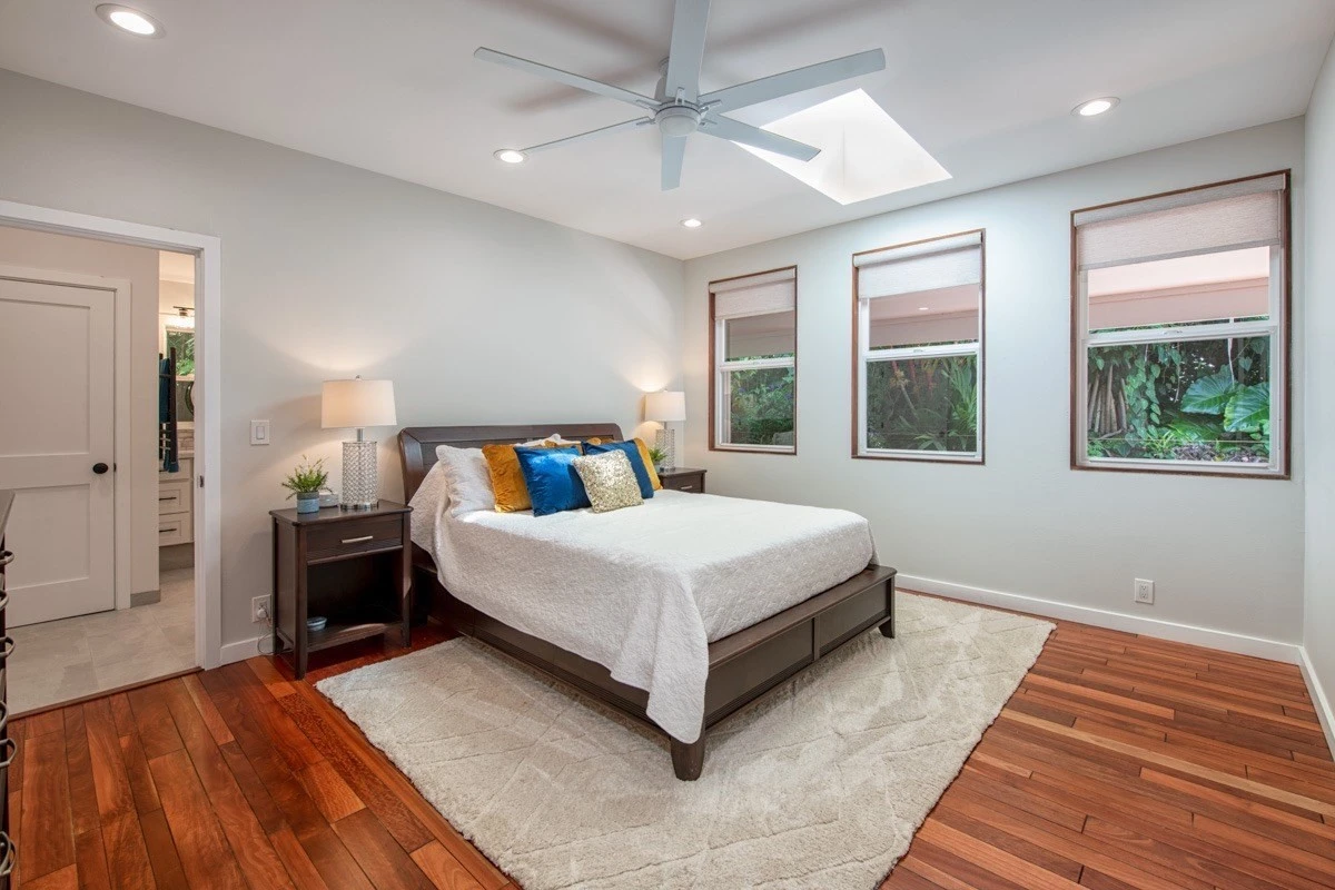 Queen bed with bright windows and ceiling fan