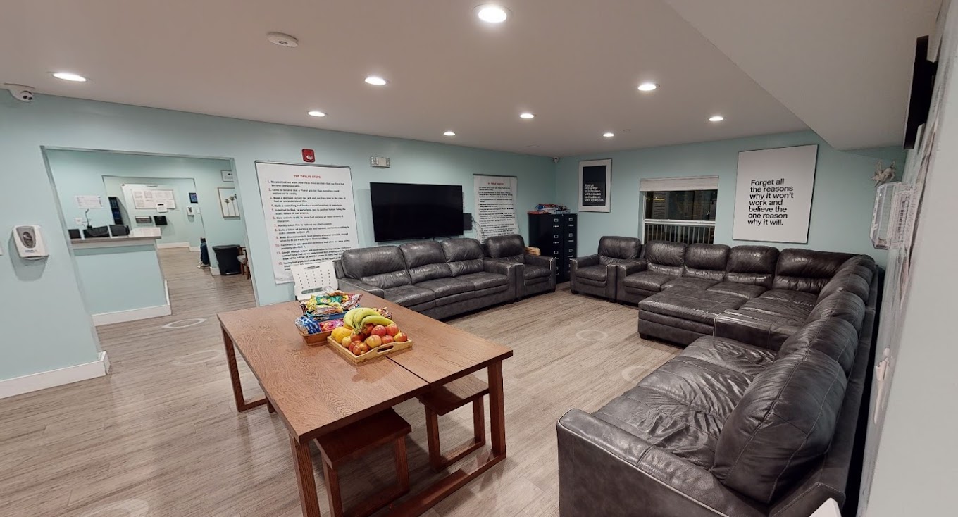 Group lounge with large sofas, fruit on table, and wall posters.