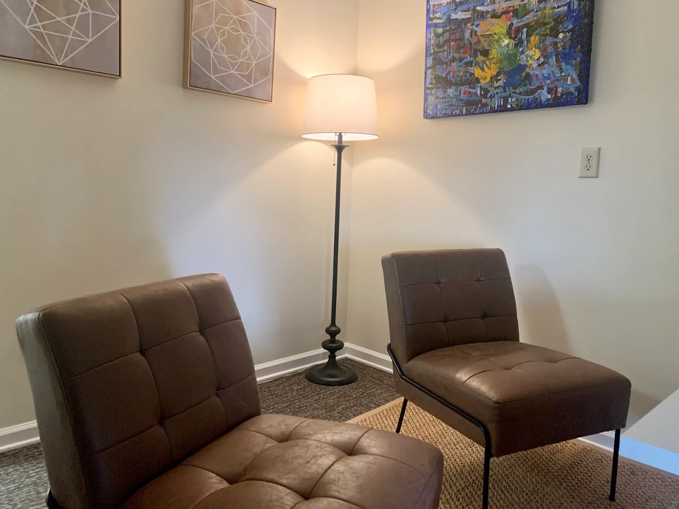 Counseling area with two chairs, artwork, and floor lamp