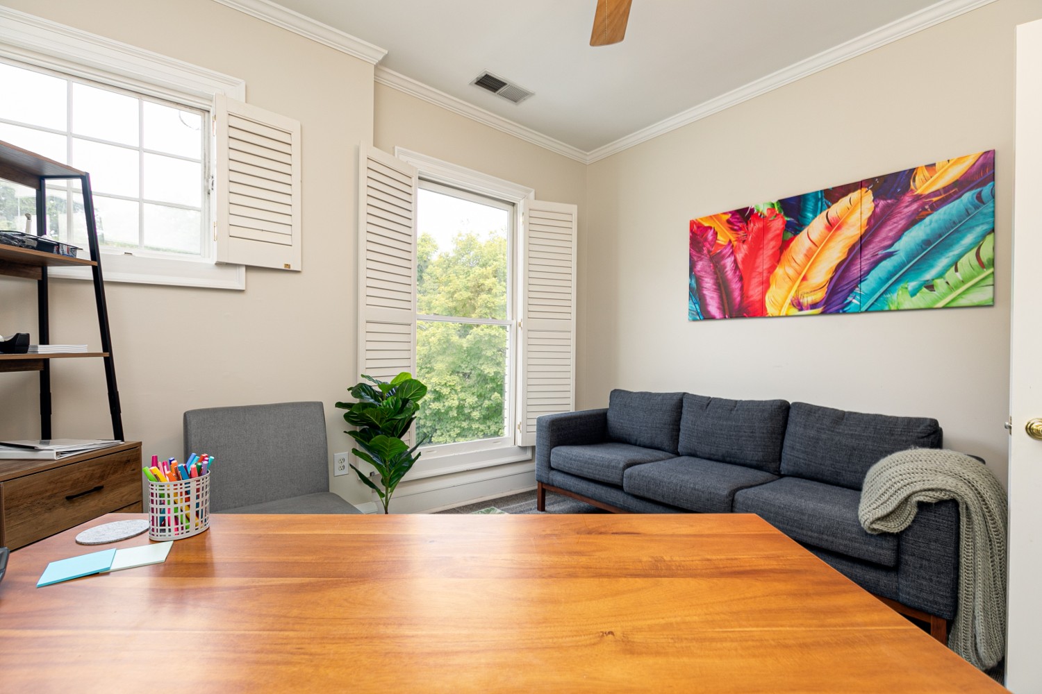 Office room with gray couch and colorful artwork