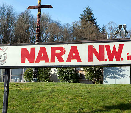 Outdoor sign reading NARA N.W. with grass and trees behind