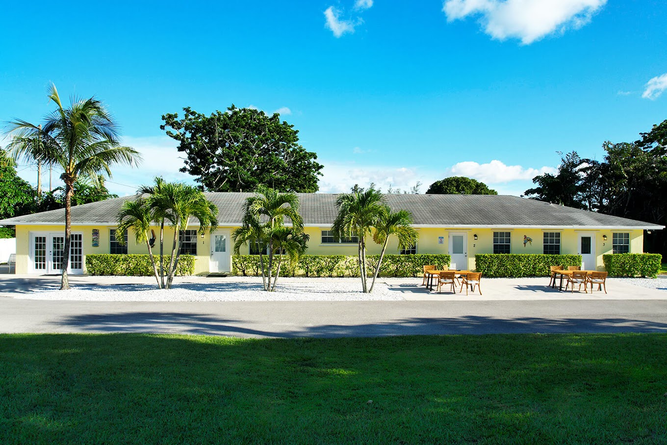Yellow rehab facility with outdoor seating and palm trees.