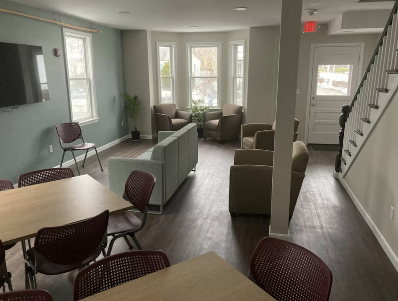 Living room with armchairs, sofas, TV, and stairs