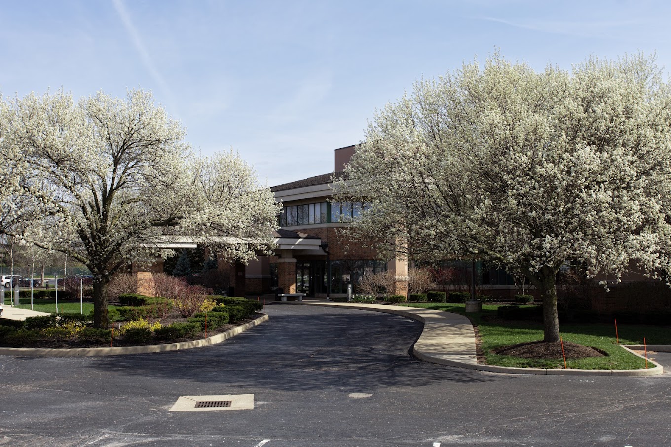 Facility entrance with circular driveway and blooming trees