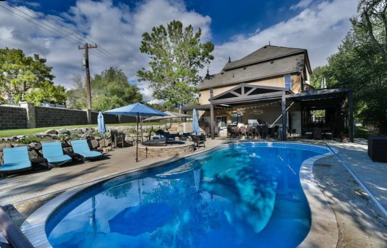 Outdoor swimming pool with patio seating and covered gathering area