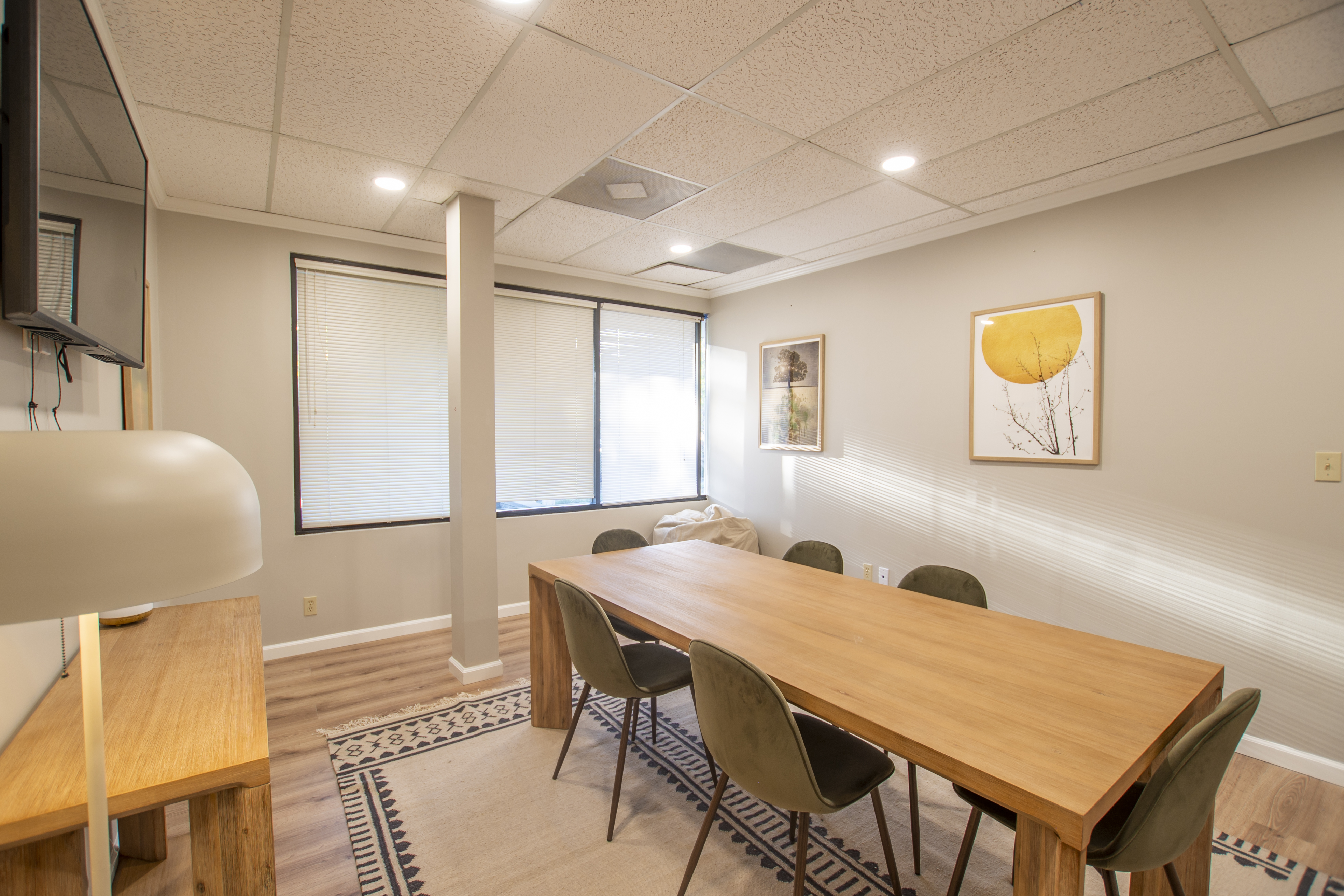 A small meeting room with a wooden table and modern artwork.