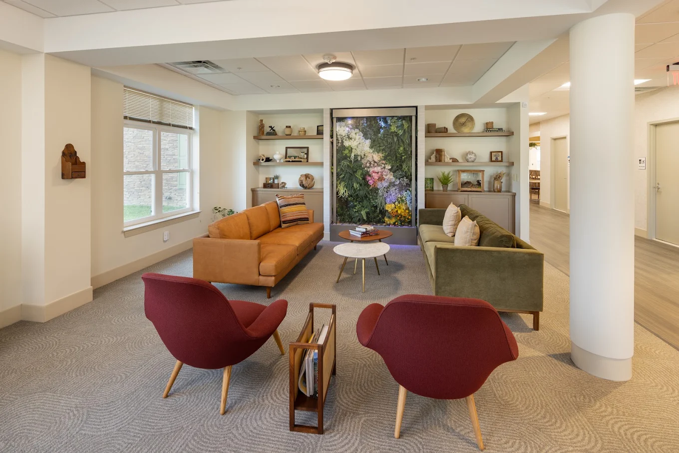 Lounge with sofas, chairs, coffee tables, and floral wall display.