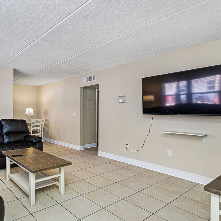 Living room with couches and table infront of a TV.