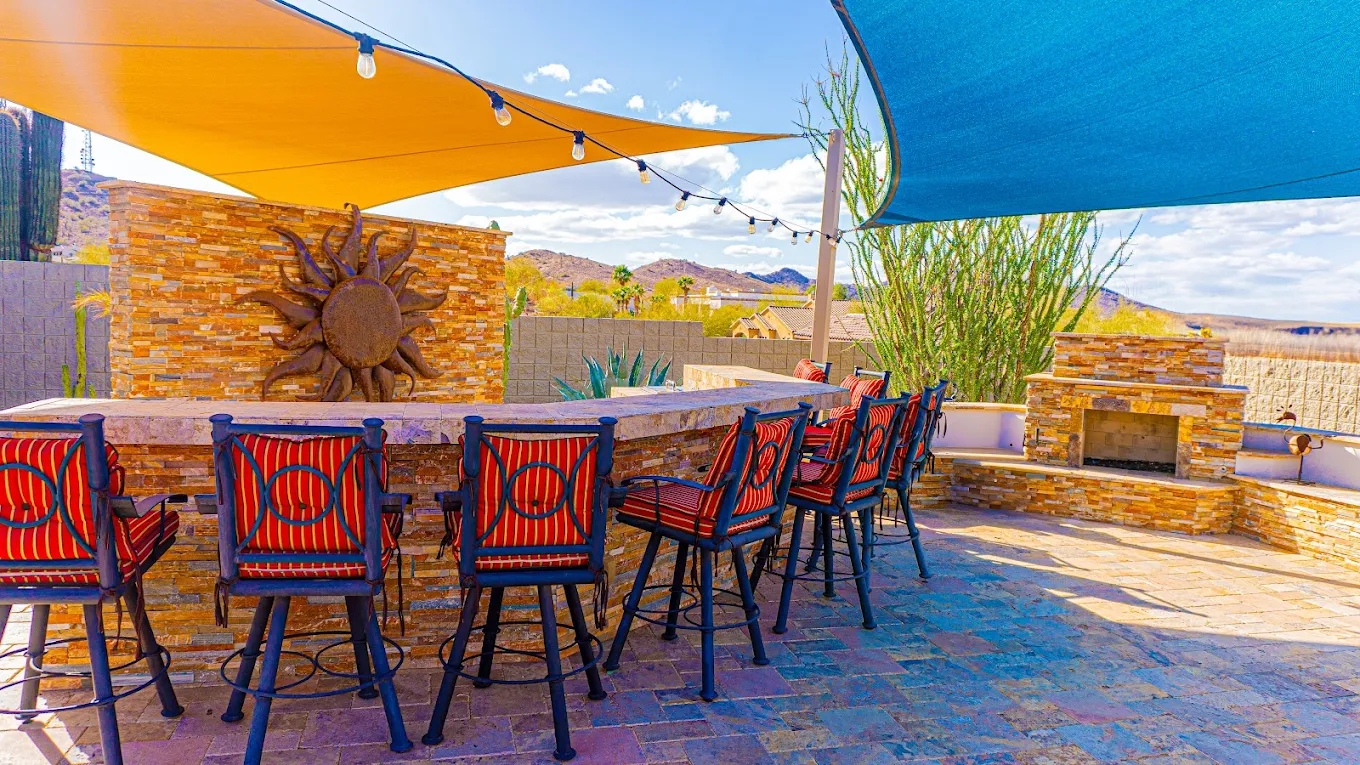 Outdoor bar with seating, fireplace, and shade canopy