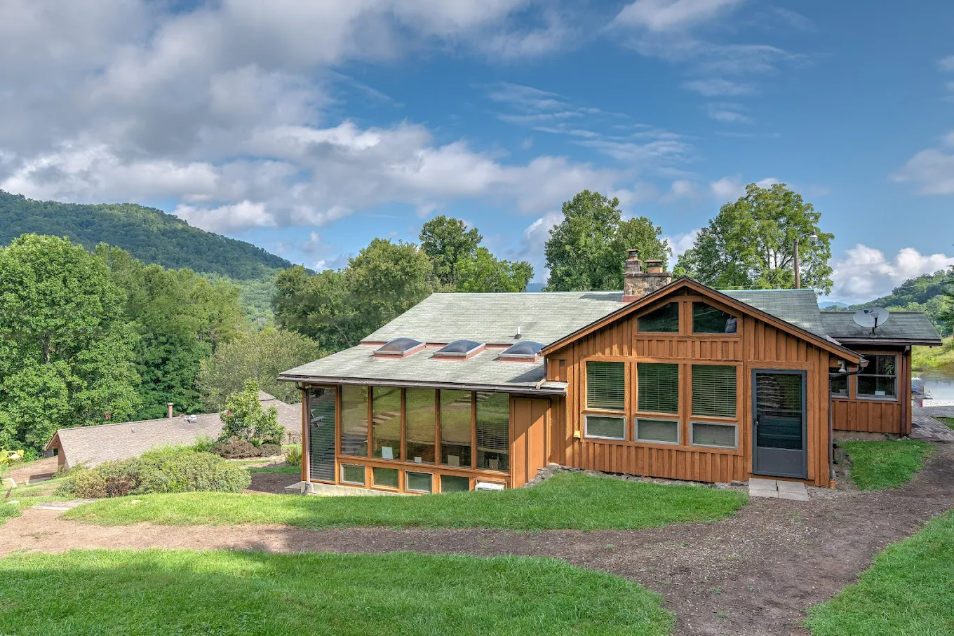 Residential lodge set on grassy hillside with mountain backdrop