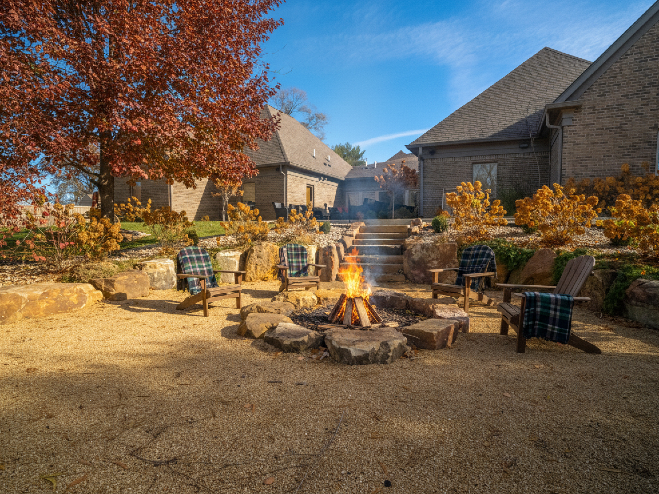 Fire pit area with chairs and autumn landscaping.