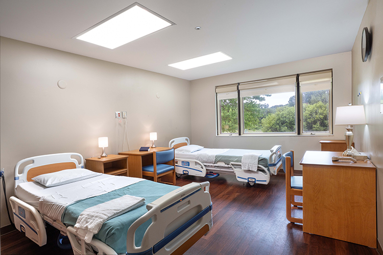 Two hospital beds in bright, spacious patient room