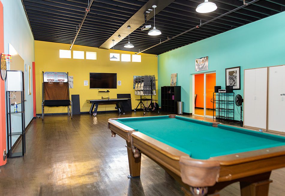 Pool table and arcade basketball in colorful game room
