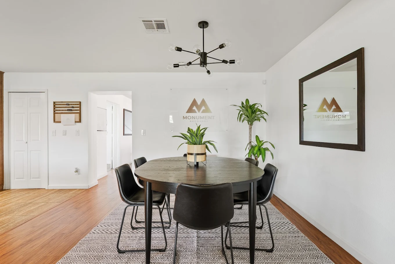Small dining area with round table, chairs, and potted plants