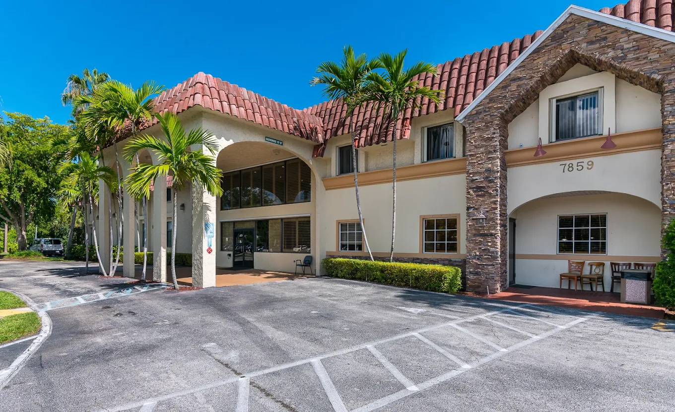 Palm-lined entrance to a large white treatment facility.