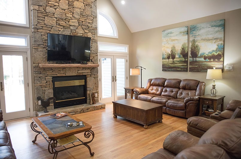 Common lounge with stone fireplace, TV, and leather seating
