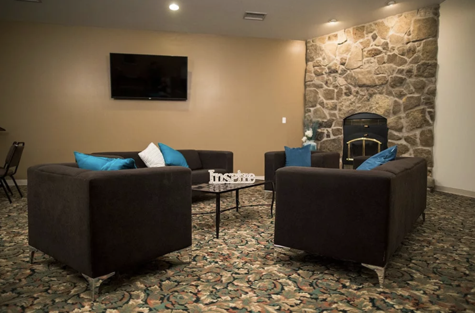 Lounge area with couches, a stone fireplace, and a TV.