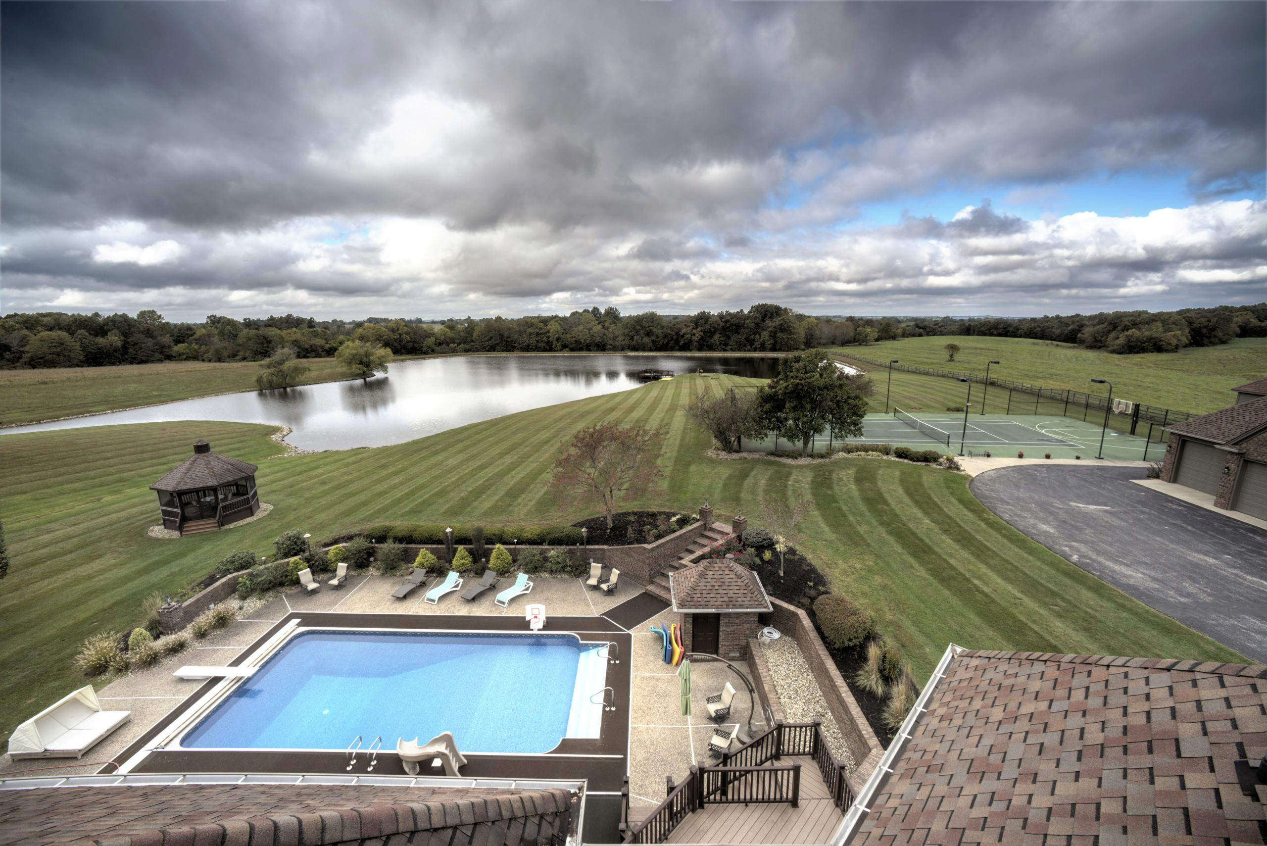 Scenic view of lake, lawns, and recreation courts from above