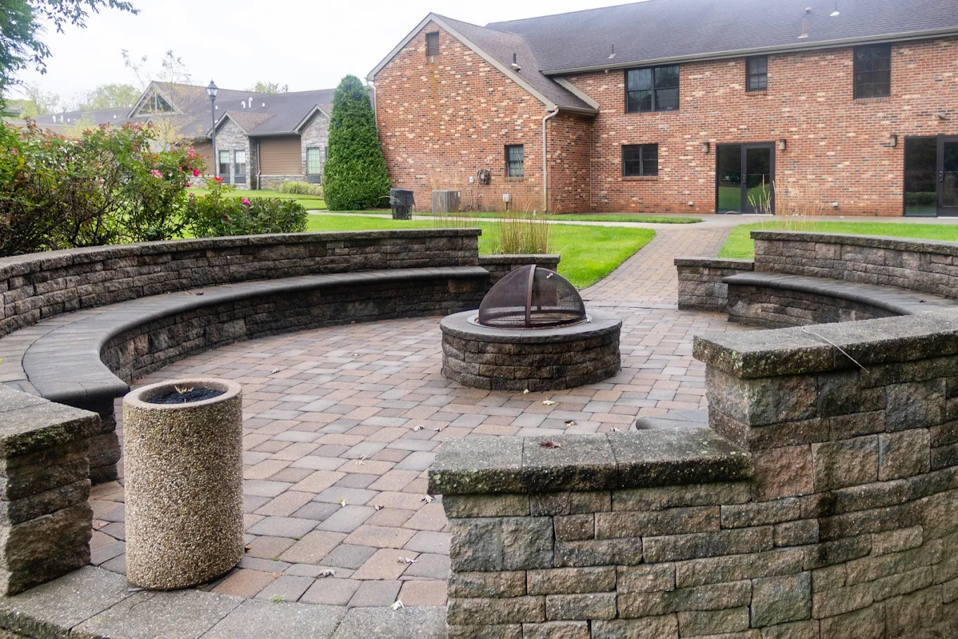 Stone fire pit with curved seating in landscaped courtyard