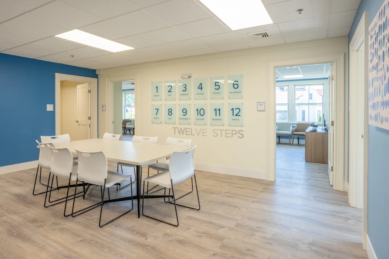 Meeting table and chairs beside a Twelve Steps wall display