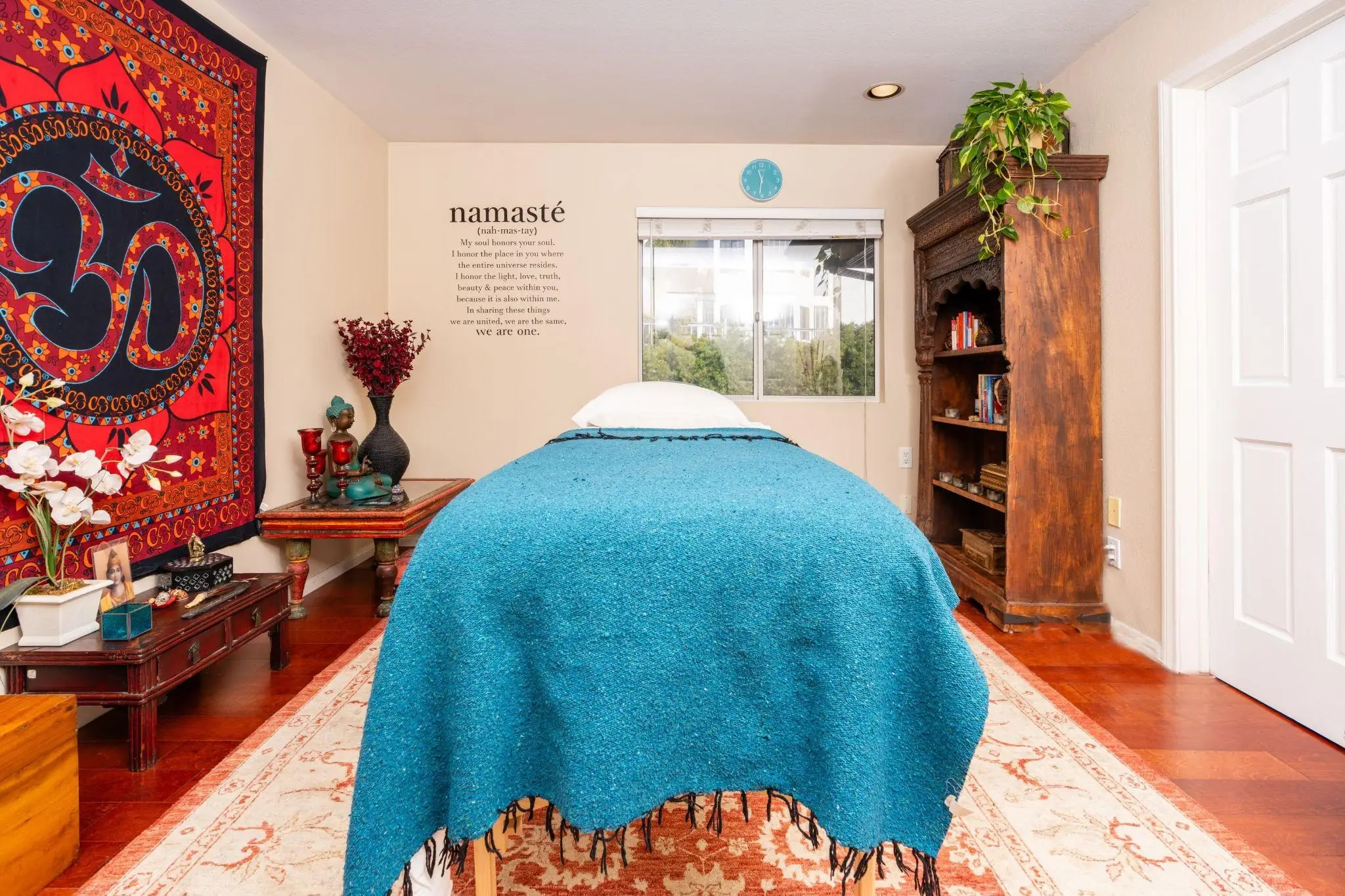 Spa room with massage table, tapestry, and warm decor accents