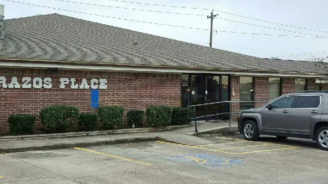 Exterior of brick building with ramp and parking spaces.