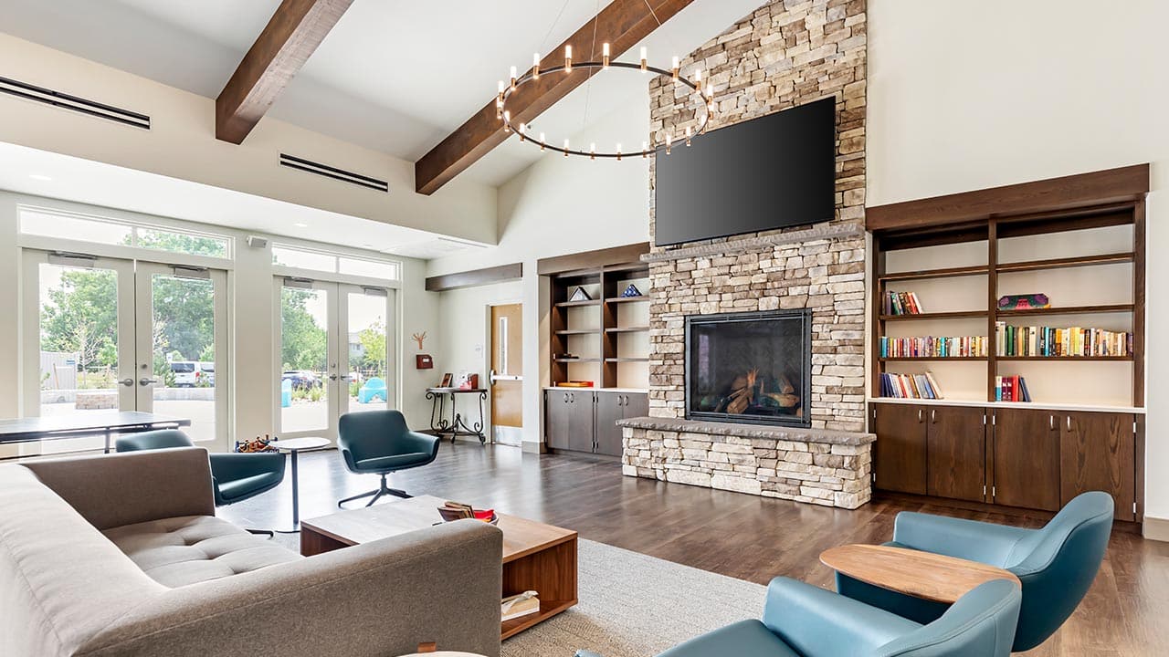 Lounge with stone fireplace, bookshelves, and large windows