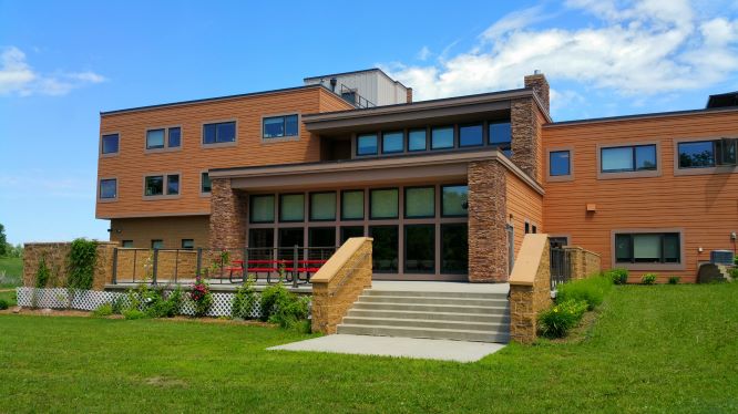 Exterior view of the rehab facility with stairs to entrance on a lawn.