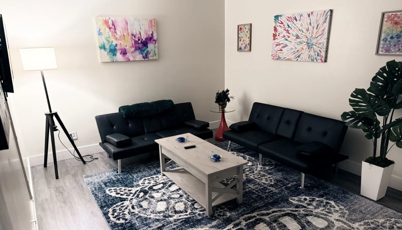 Cozy therapy room with black sofas and colorful artwork.