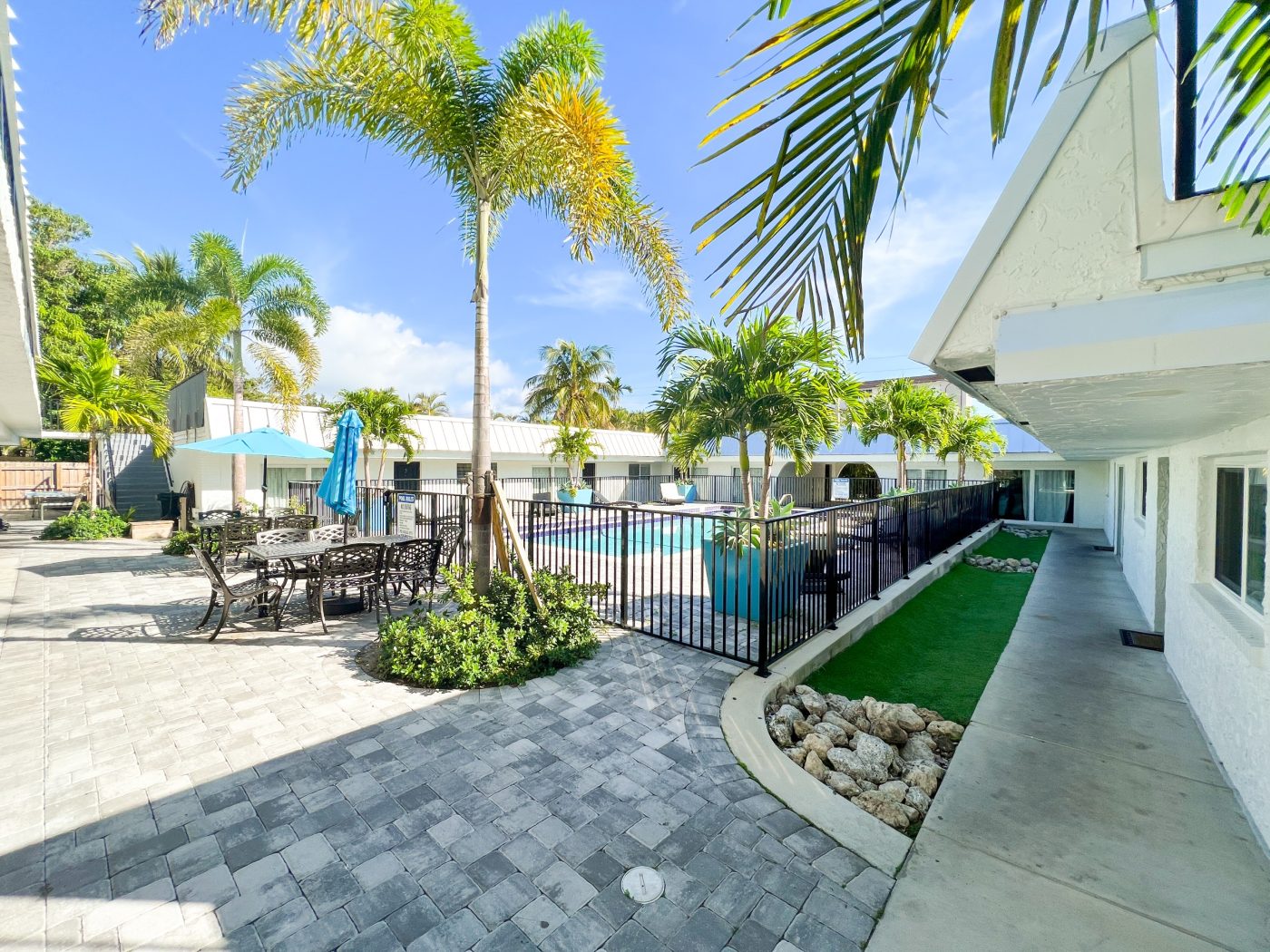 Outdoor courtyard with pool, palm trees, and patio seating at treatment center