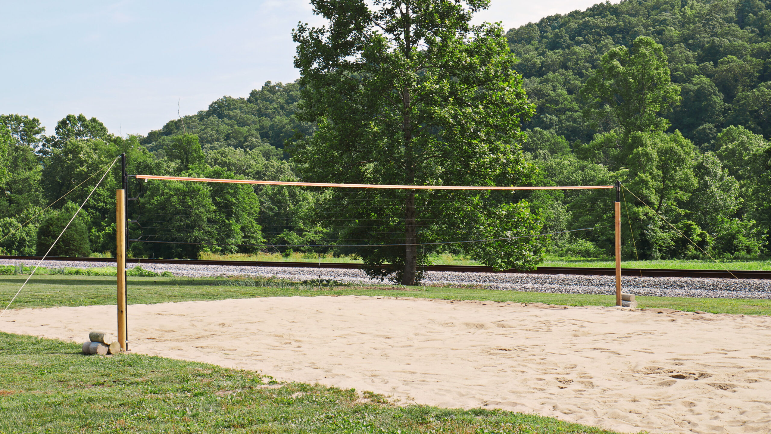 Outdoor sand volleyball court surrounded by trees