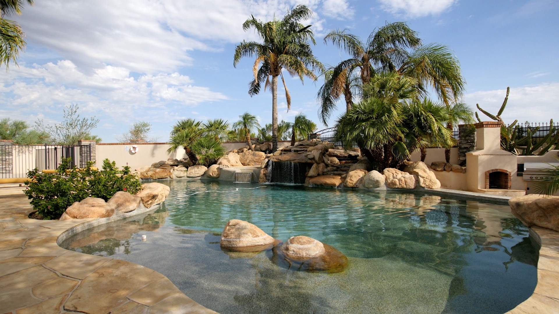 Outdoor pool with rock waterfall and surrounding palm trees