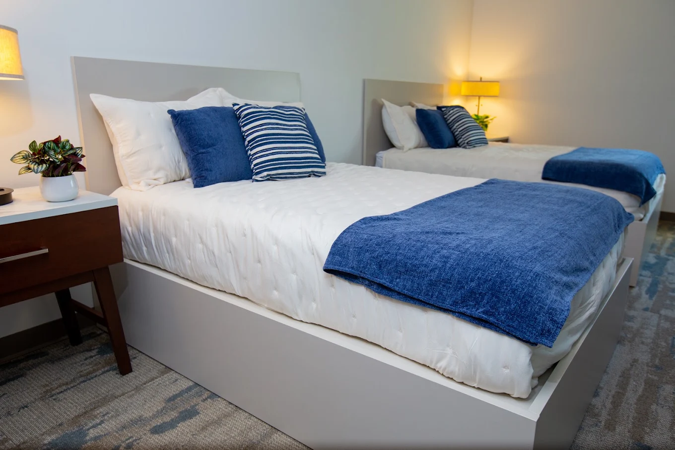 Shared bedroom with two beds and blue blankets and pillows