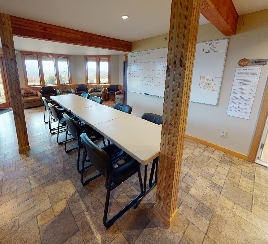 Meeting room with tables, chairs, and whiteboard for group sessions