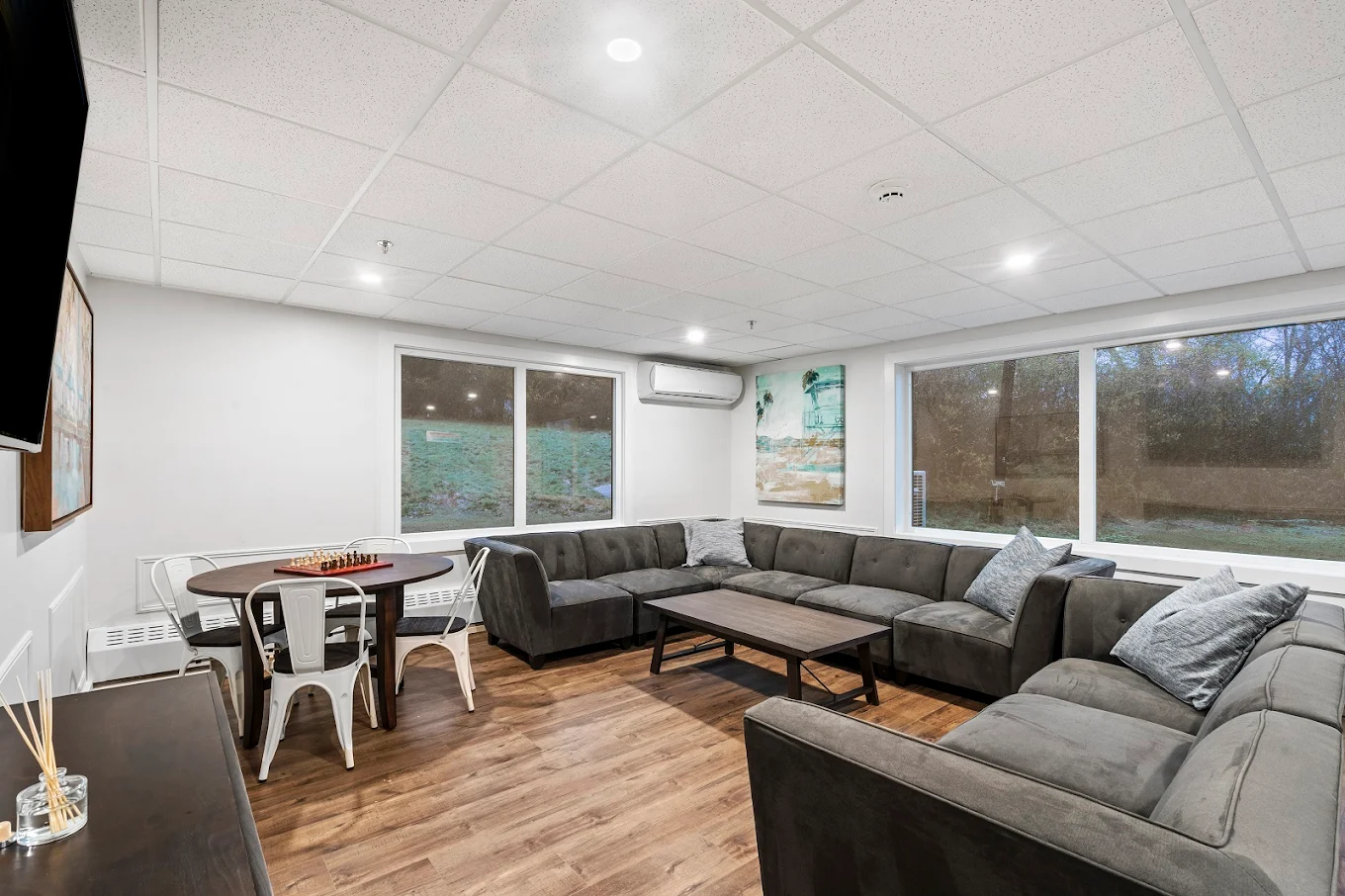 Large gray sectional sofa and game table in a well-lit community space