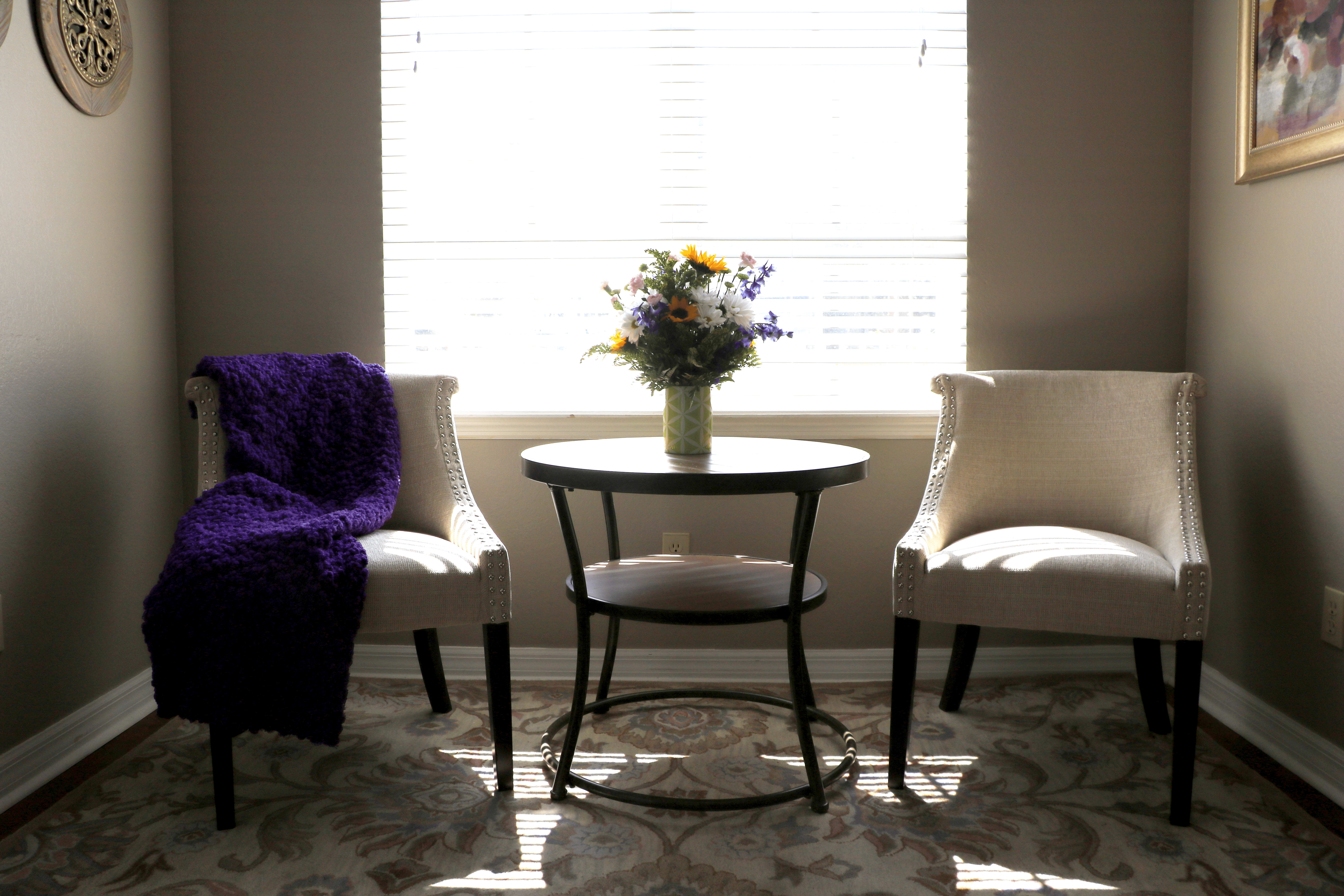 Two chairs and table with flower vase near window