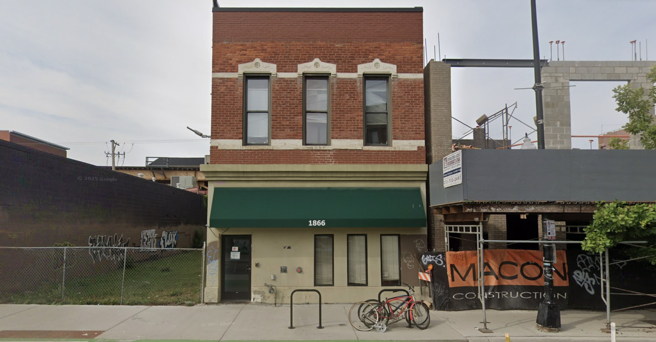 Red brick rehab facility with green awning and street view.