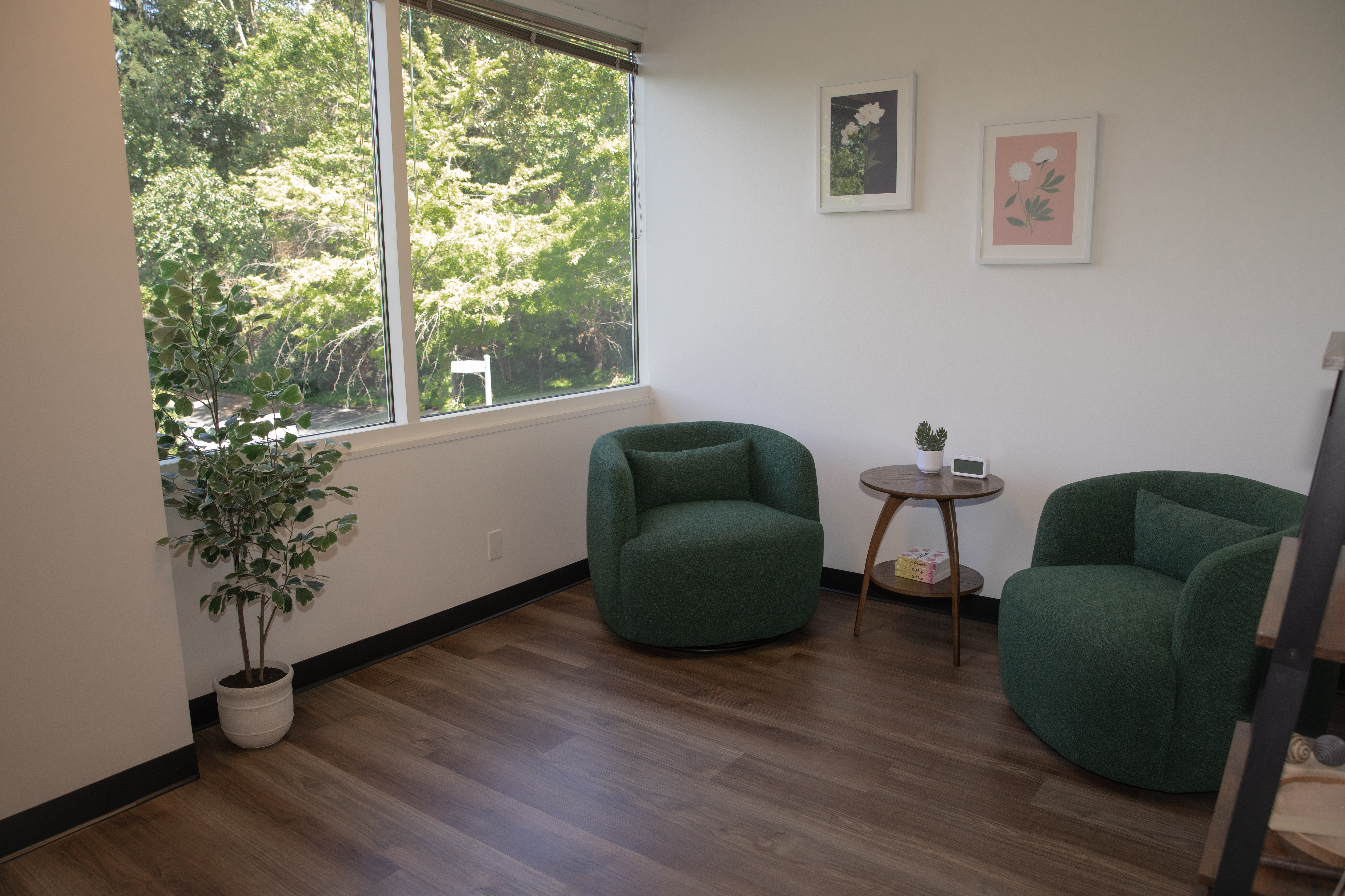 Two green chairs by a window with small table and plant