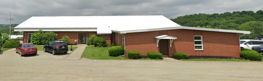 Brick building with white roof and cars parked in front