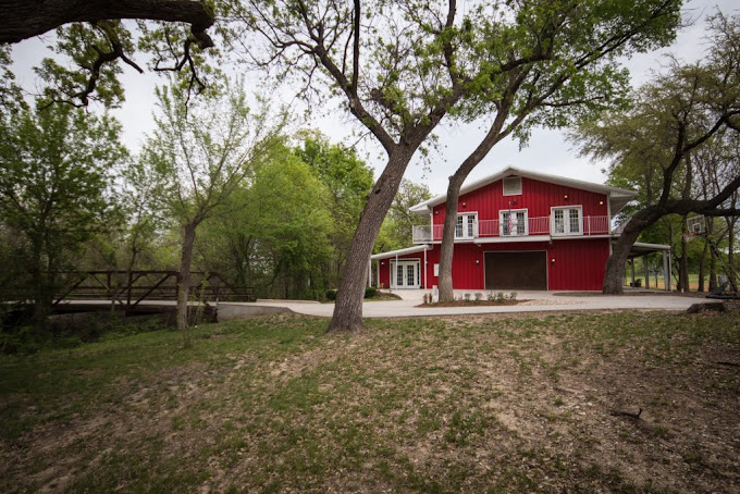 Red facility building among trees and grass