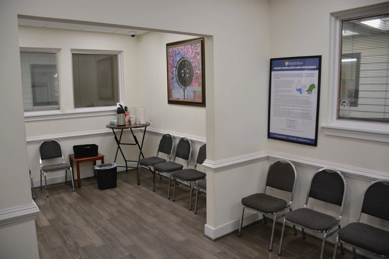 Waiting room with rows of chairs, wall art, and refreshment table