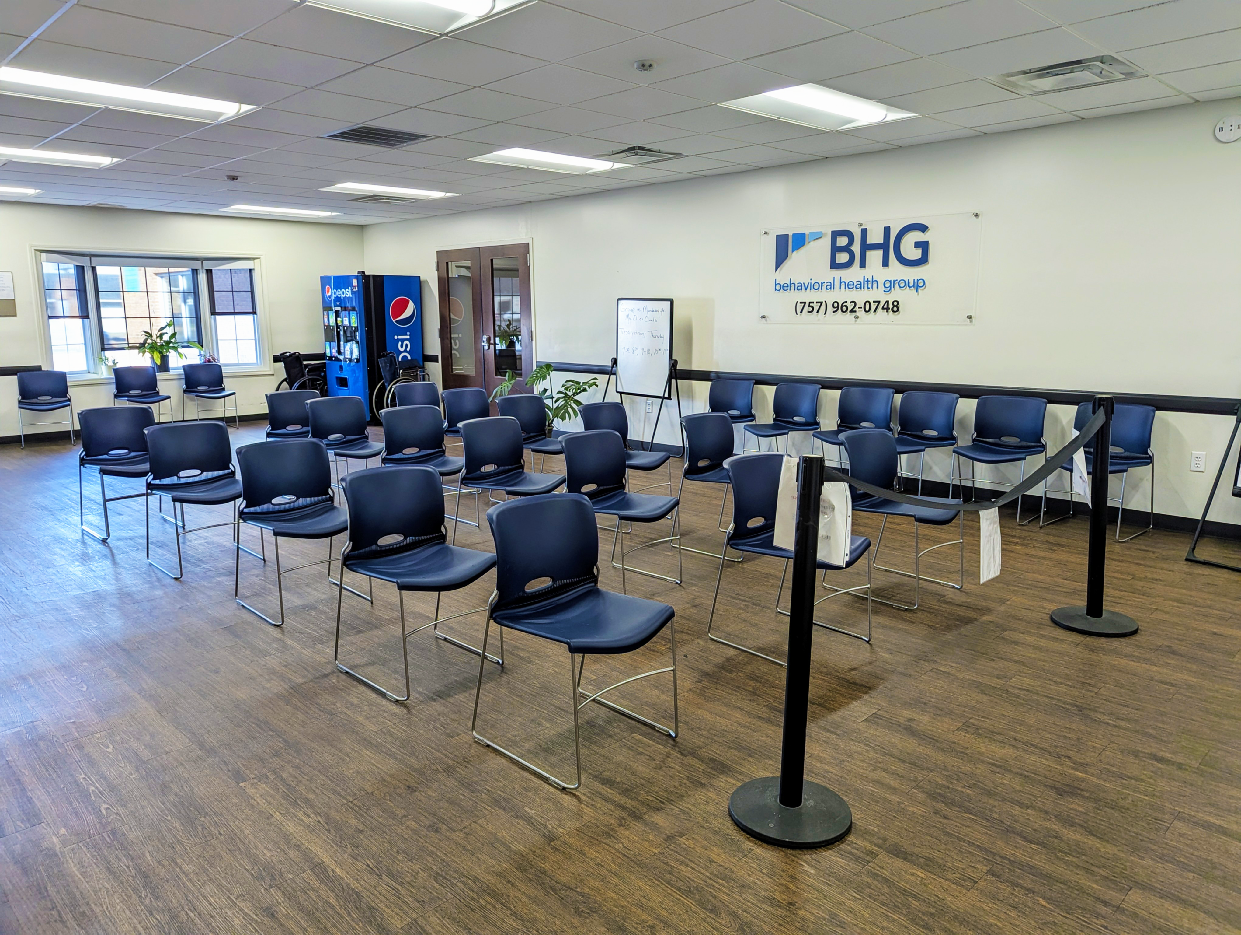 Waiting area with rows of chairs and beverage vending machine