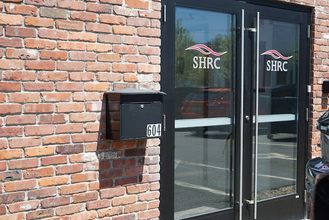 Outdoor view of building’s entrance with parking lot. ​​